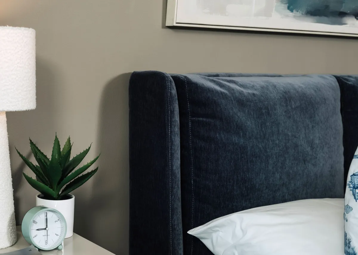 A lifestyle closeup of the Tolka lamp and the padded headboard on the Comfy blue bedframe.