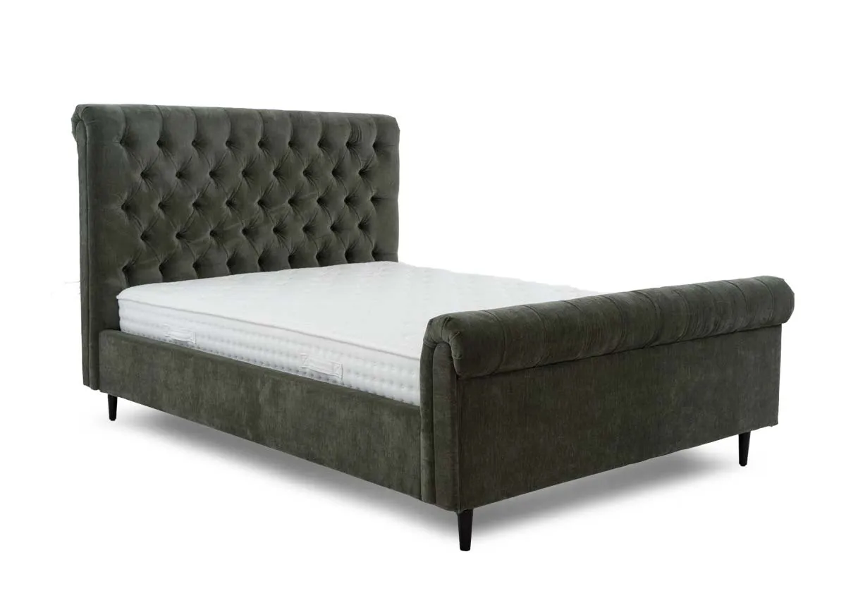 A green fabric bedframe with tufted Chesterfield detail and scrolled finish head and footboard. Angled view of EZ Livings Furnitures Sofia bed.
