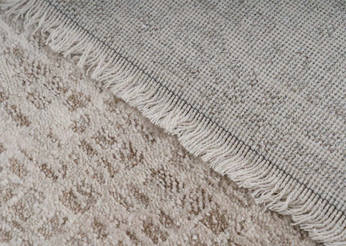 A beige and taupe distressed rug from EZ Livings Flowline range. Closeup of fringe detail on border