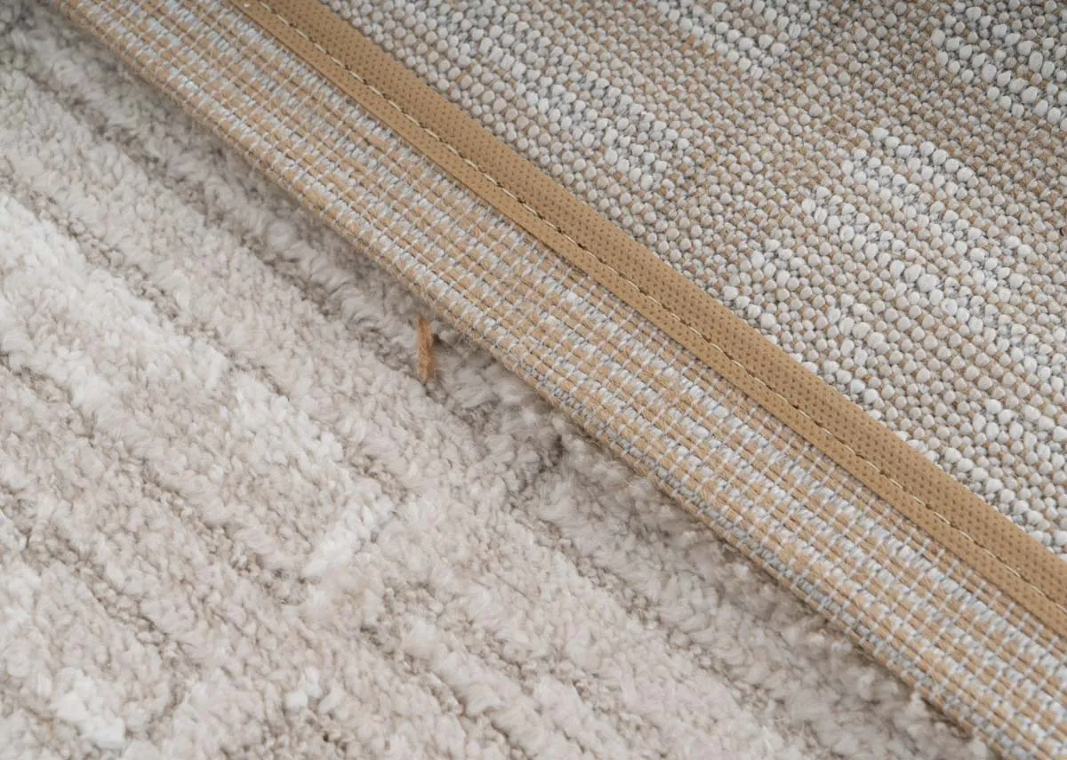 A beige and taupe distressed rug from EZ Livings Sable range. Closeup of underlay and pile detail on border
