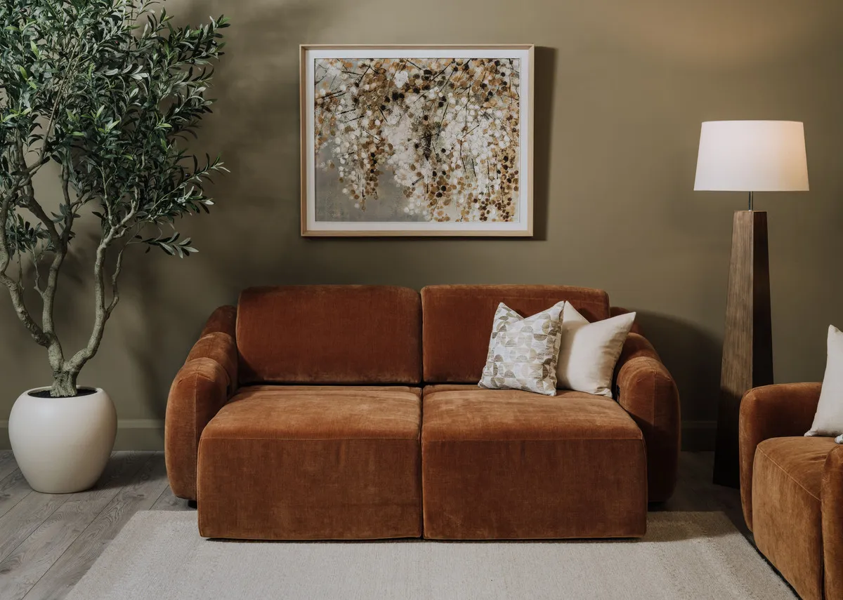 A lifestyle image of the Eleanor rust 2 seater with left and right side as a cinema chaise with Bliss painting and Eleanor armchair.