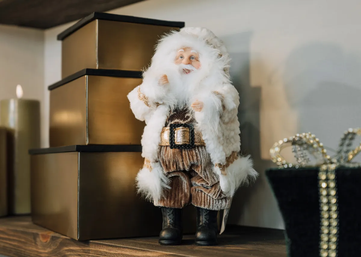 A lifestyle image of the Santa Claus figurine with a set of 3 gold boxes
