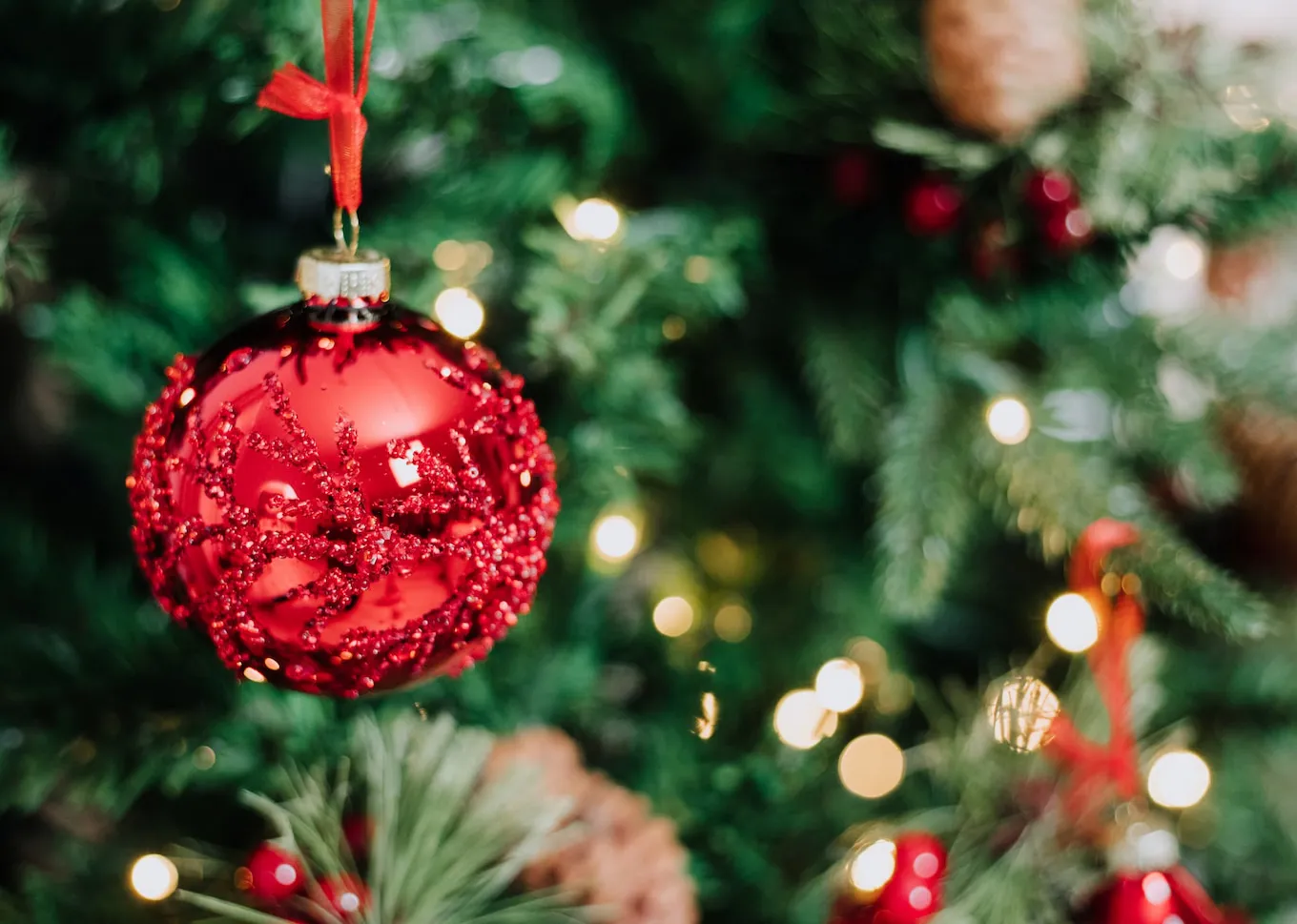 A lifestyle image of the Home for The Holidays red bauble on a tree