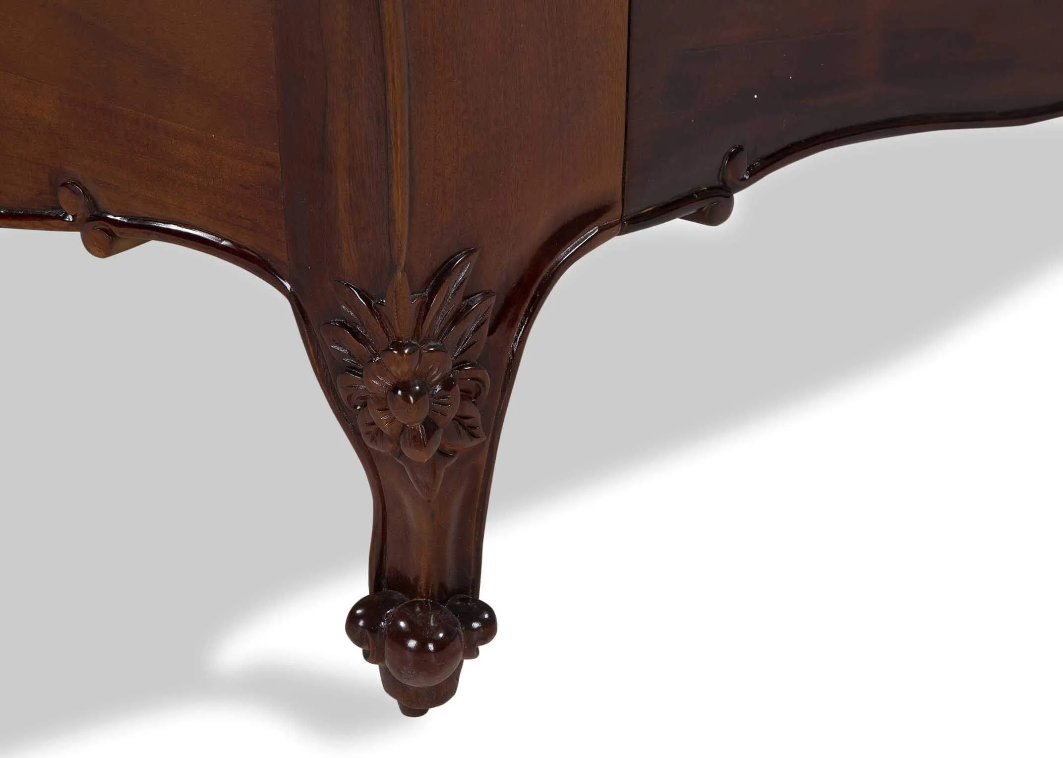 Detailed view of leg of the Lyon two-tone king size mahogany wood and cream leather bedframe with curved feet