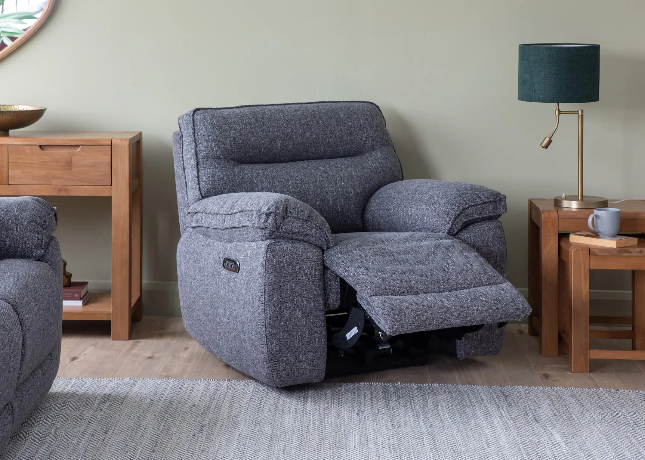 A lifestyle image of the Cairms Grey Fabric Power Recliner with Tiverton lamp