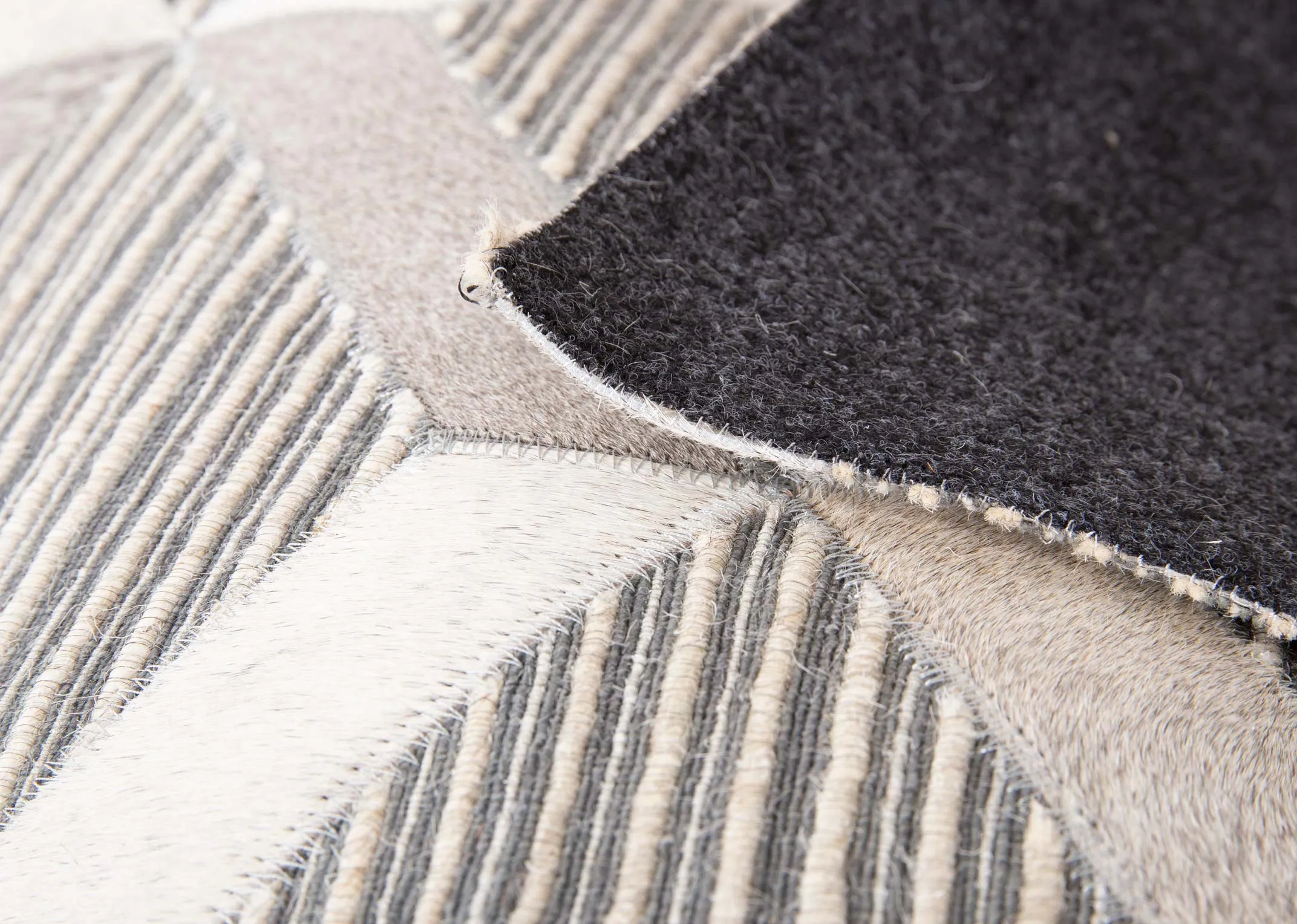 A silver & grey geometric hair on Hyde rug from EZ Living's Corbit range. Closeup shows leather underlay