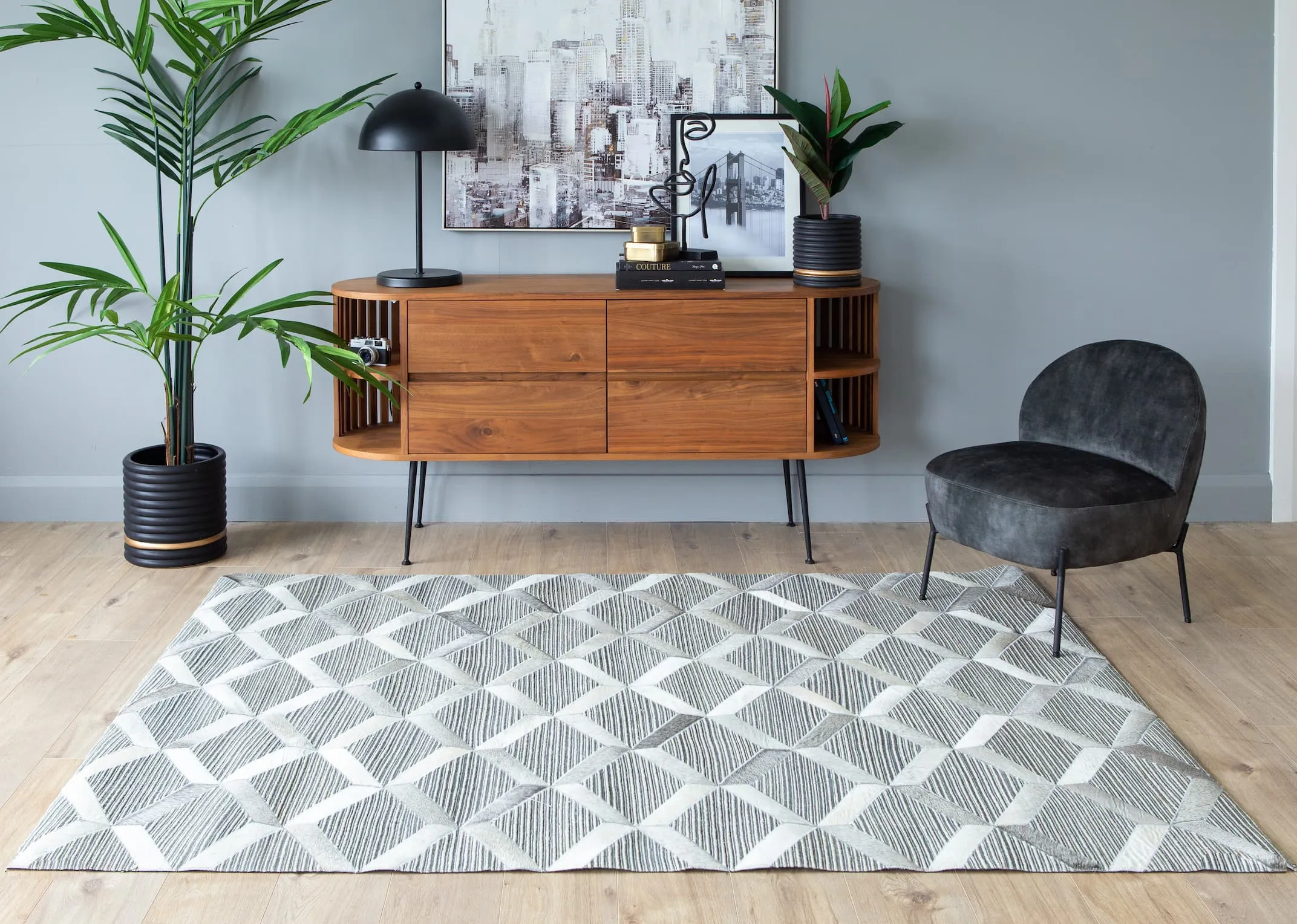 A lifestyle image of the Corbit Grey Marine rug with recap sideboard with Sarsfield lamp & City scape print.