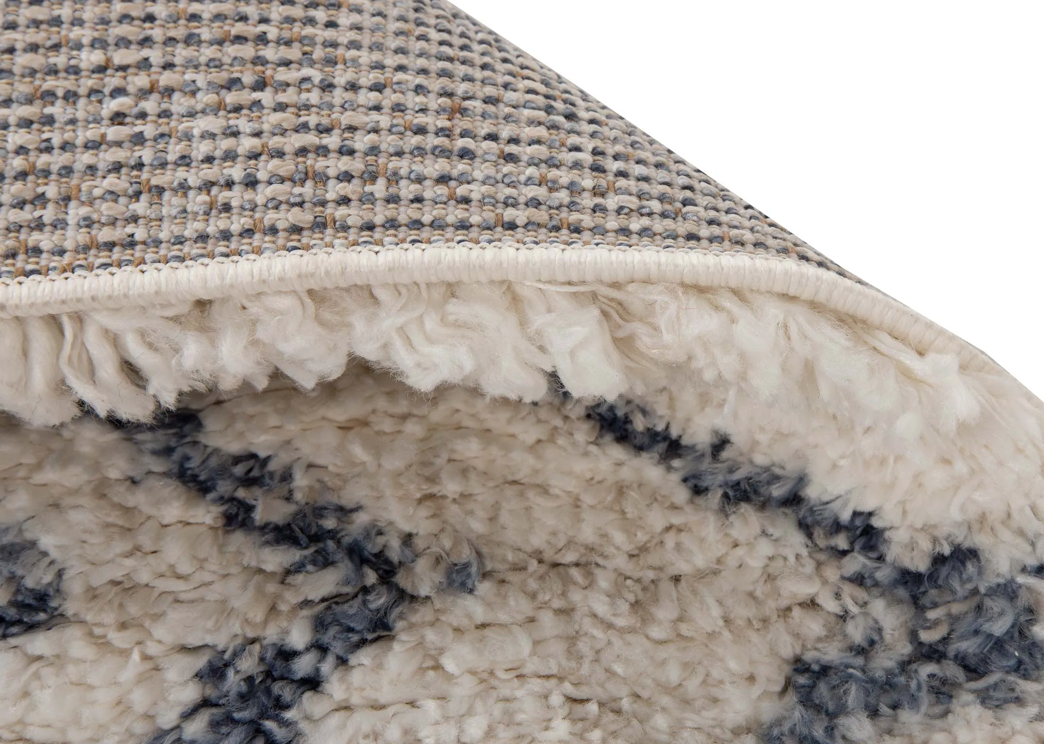 A creamy white deep pile rug with blue Aztec print from EZ Livings Sula range. Closeup of underlay