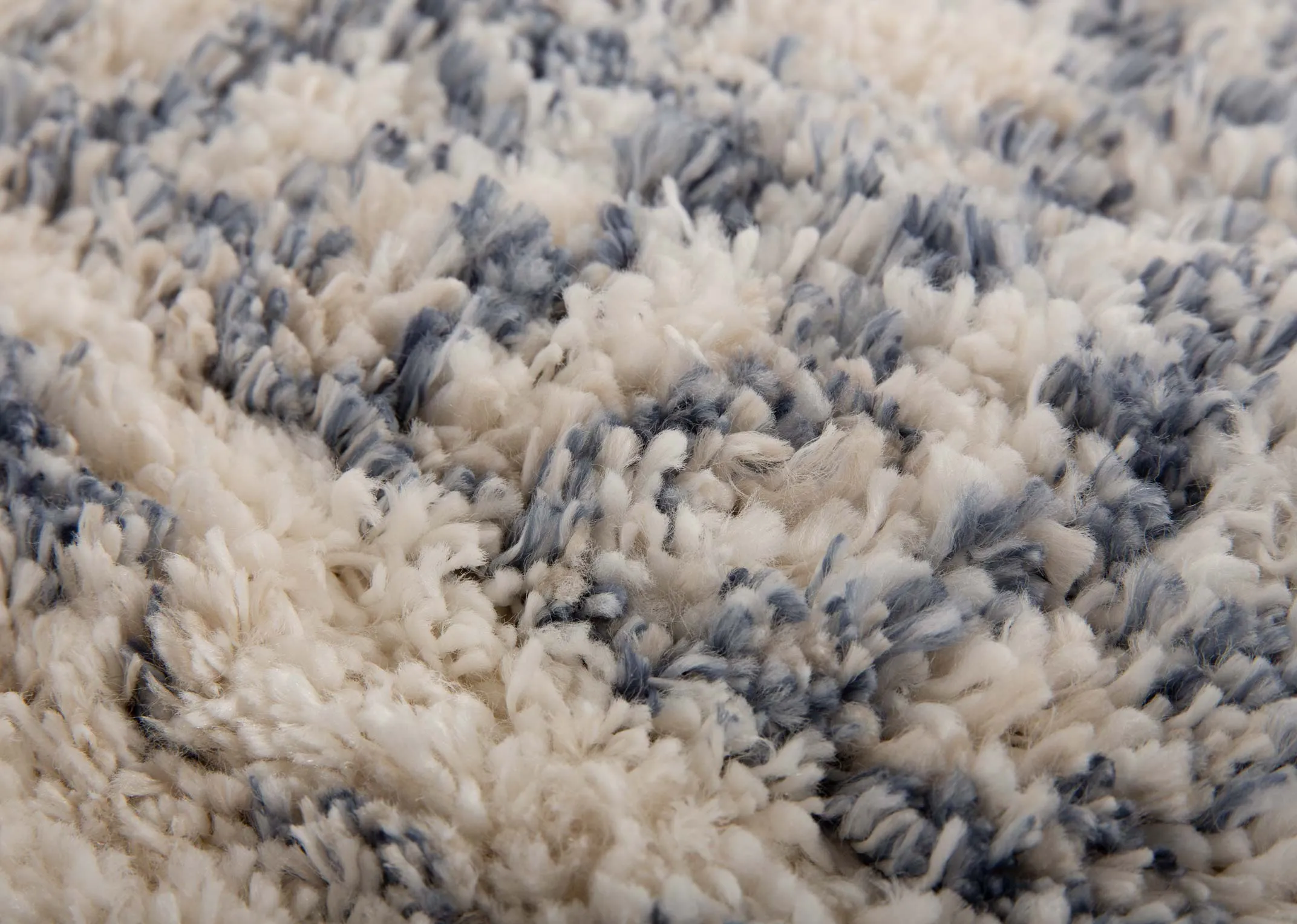 A creamy white deep pile rug with blue Aztec print from EZ Livings Sula range. Closeup of soft texture