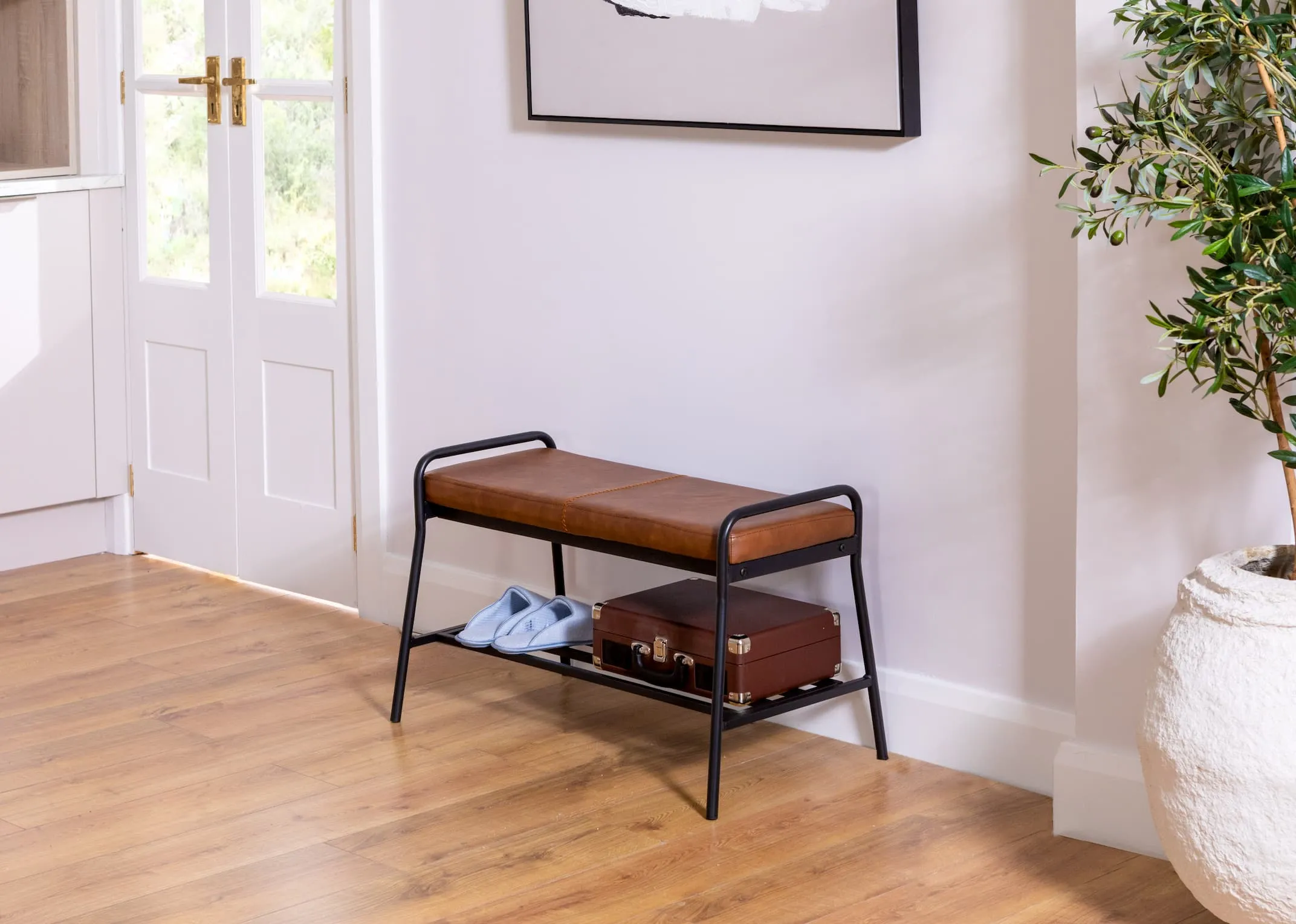 A lifestyle image of the Salthill PU bench with slippers and suitcase in a utility or kitchen setting.