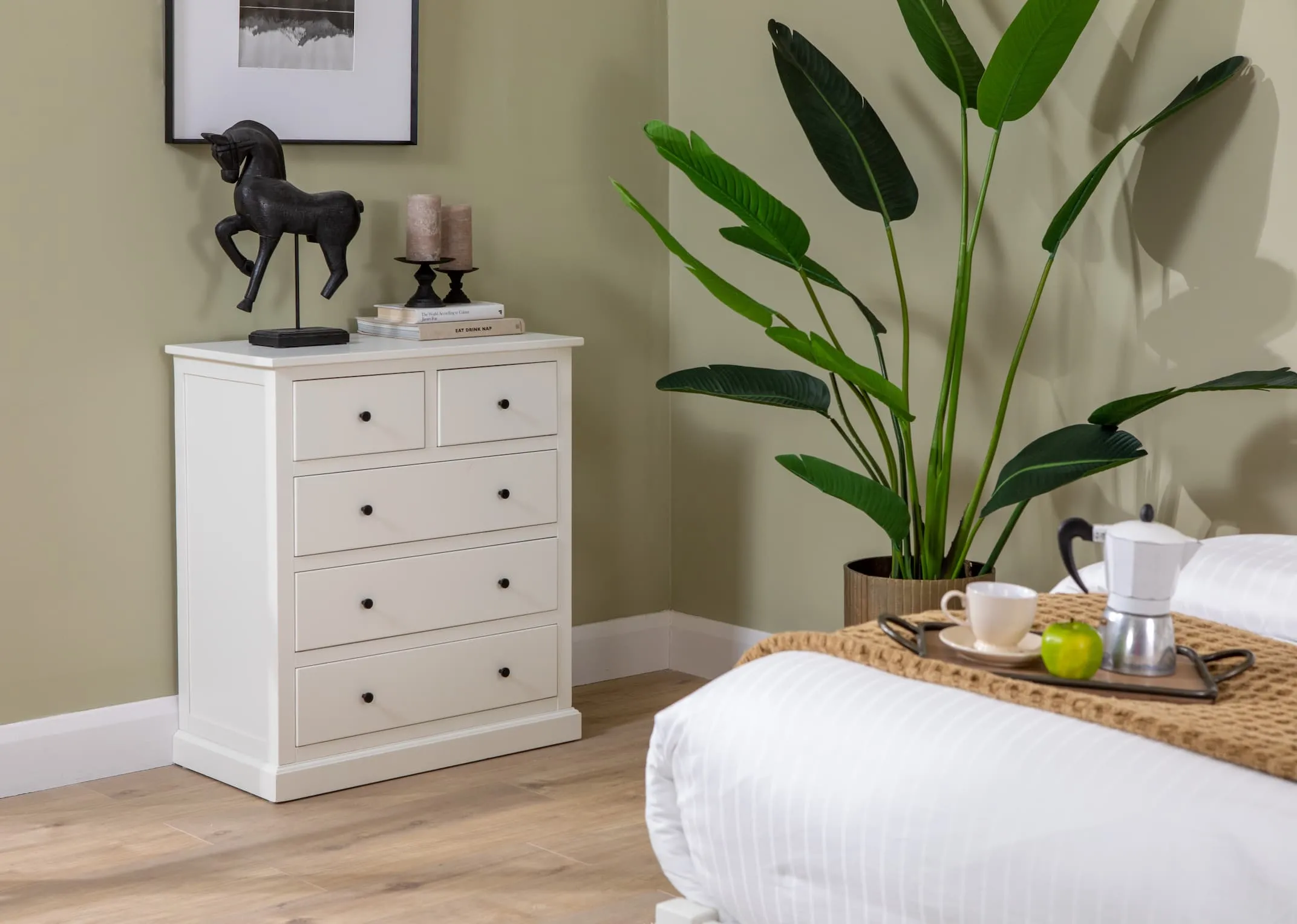 A lifestyle image of the White Atlas bedroom range including bedframe & chest of drawers with a selection of home accessories