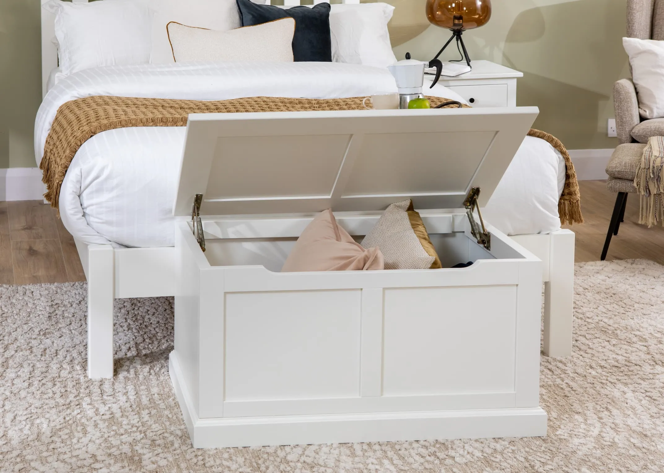 A lifestyle image of the White Atlas bedroom range including bedframe & open blanket box showing cushions