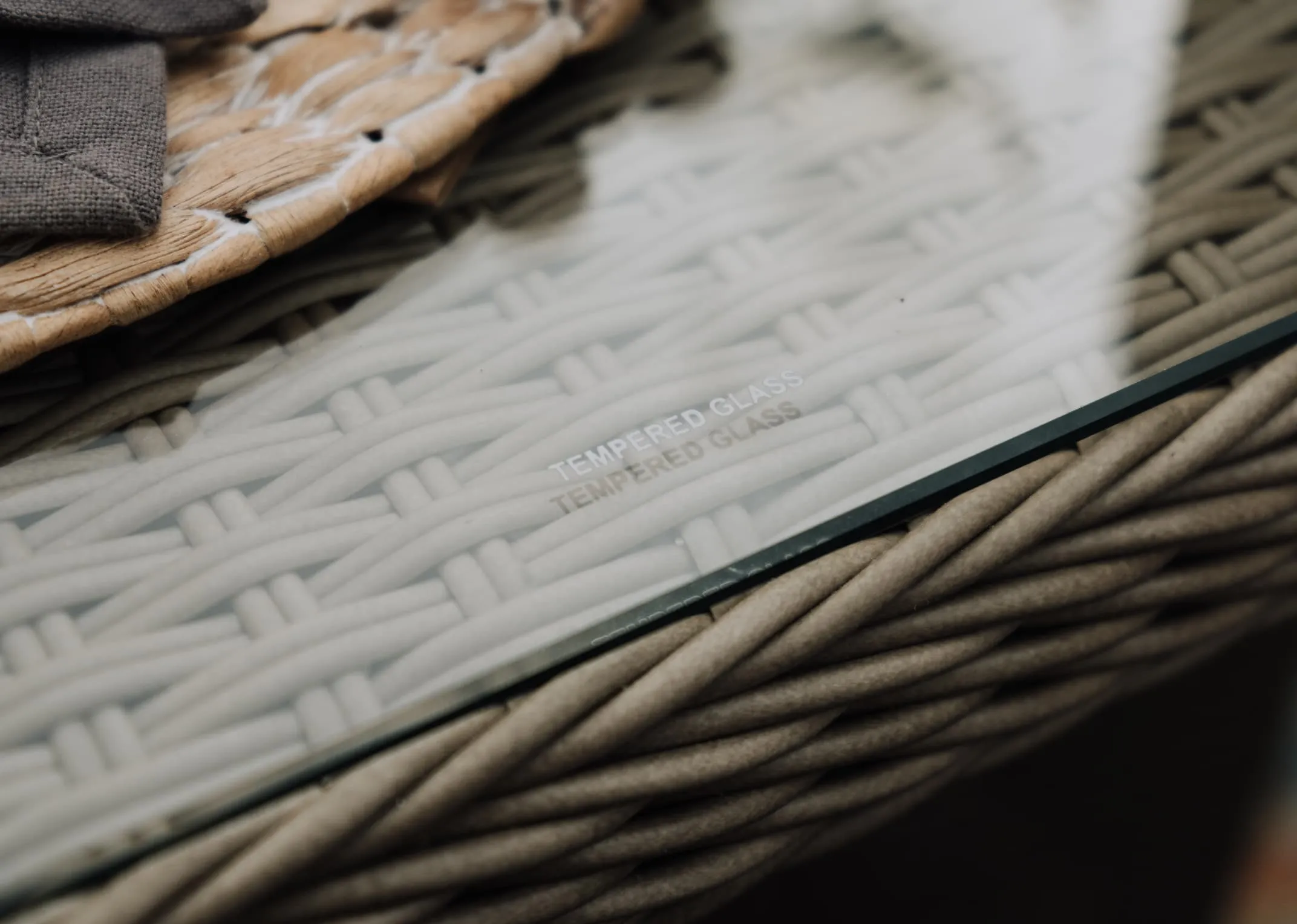 A wicker corner garden sofa with a square dining table & 2 ottoman benches from EZ Livings Marbella range. Front view of curved armrests on either end.