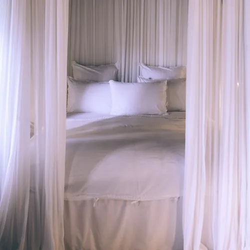 Bed with duvet, pillows, and curtains.