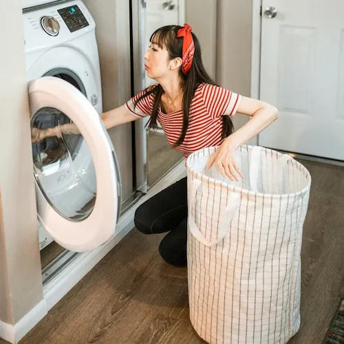 Woman loading washing machine.