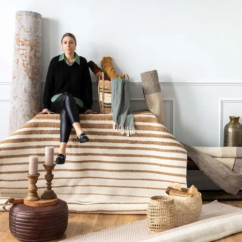 Woman sitting on a selection of rugs from EZ Living Furniture.