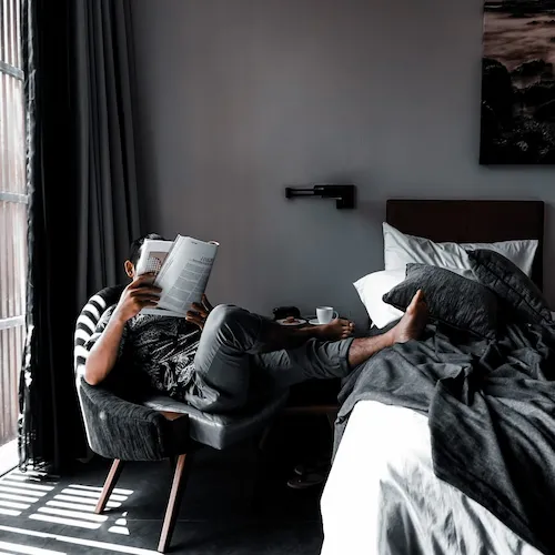 Black painted room with man reading a magazine.