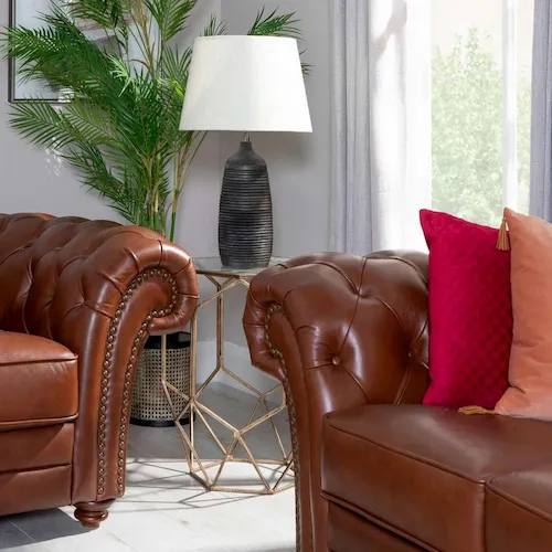Red and blush coloured cushions on leather sofas from EZ Living Furniture.