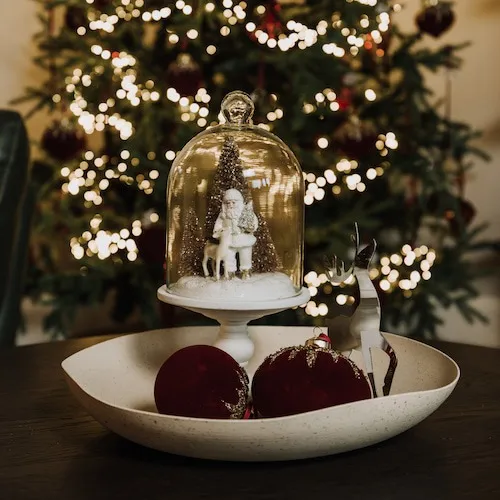 Red velvet and gold glitter baubles in a bowl with other seasonal ornaments at EZ Living Furniture.