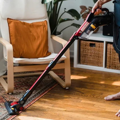 Hoovering the floor with rug. 